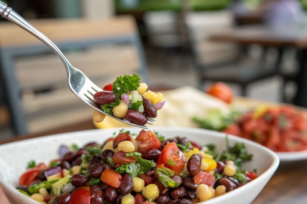 Fork lifting a colorful bite of dense bean salad.